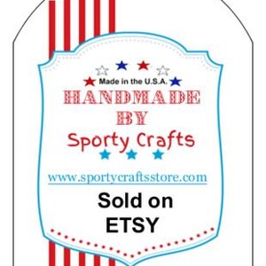 Może przedstawiać: Czerwono-biało-niebieska etykieta w kształcie tarczy z tekstem "Handmade by Sporty Crafts" i stroną internetową "www.sportycraftsstore.com". Etykieta zawiera r&oacute;wnież tekst "Made in the U.S.A." i "Sold on ETSY".