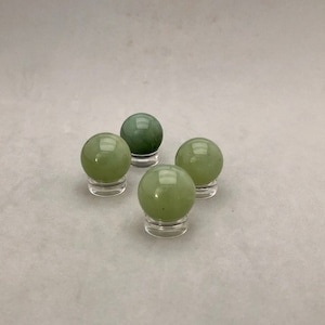May include: Four green jade spheres on small clear stands. The spheres are smooth and polished.