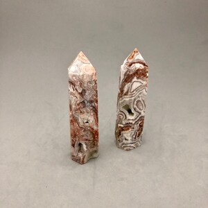 May include: Two white and brown agate crystal points, also known as banded agate, with a pointed tip and a flat base.