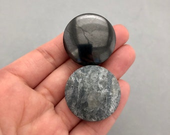 May include: Two round, smooth, polished stones. One is black and the other is gray with white streaks.