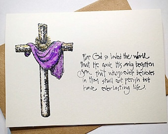 May include: A white card with a hand-drawn image of a cross with a purple cloth draped over it. The card has the text "For God so loved the world that he gave His only begotten son that whosoever believes in Him shall not perish but have everlasting life."