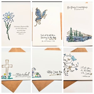 May include: Six greeting cards with different designs and inspirational quotes. The cards feature a blue flower, a butterfly, a cross, a child gardening, a mountain scene, and a floral design with butterflies. The quotes include "Seek first the Kingdom of God", "Each of us will be a blessing to the other", "Be strong and courageous", "Jesus Loves You", "You are inscribed on the palm of His hand", and "Let all you do be done with love".