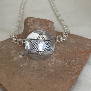 May include: A silver chain necklace with a hammered silver pendant featuring a Star of David design.