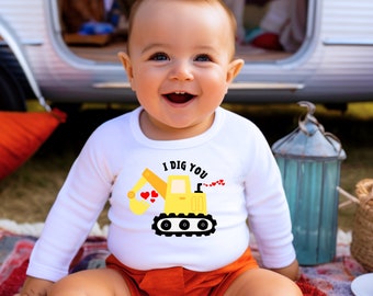 May include: A white long-sleeved onesie with a yellow construction vehicle graphic and the text "I DIG YOU". A baby is wearing the onesie and smiling.