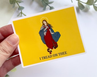 May include: A yellow sticker with a depiction of a woman standing on a snake with the text "I Tread On Thee".