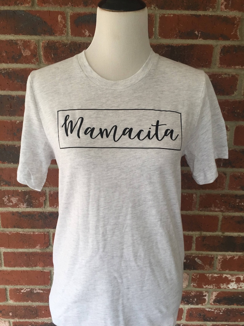 May include: A heather grey t-shirt with a black box and the text "Mamacita" in a cursive font.