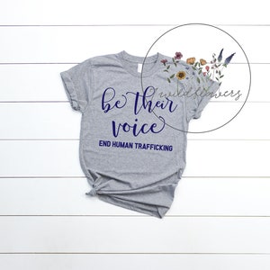 Puede incluir: Camiseta gris con el texto "be their voice" en letras azul marino y el texto "END HUMAN TRAFFICKING" en letras azul marino m&aacute;s peque&ntilde;as.