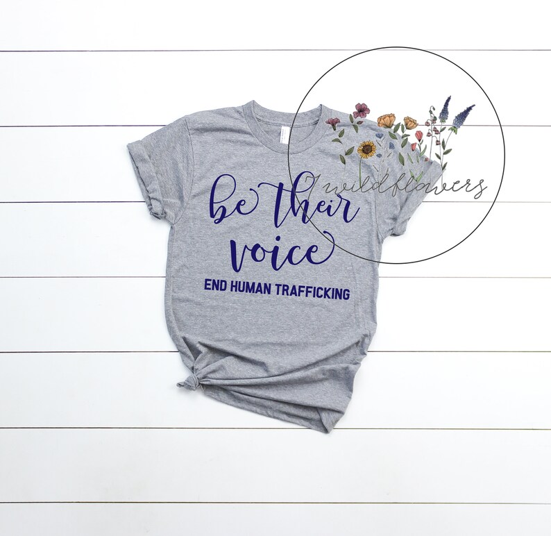 Puede incluir: Camiseta gris con el texto "be their voice" en letras azul marino y el texto "END HUMAN TRAFFICKING" en letras azul marino m&aacute;s peque&ntilde;as.
