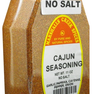 May include: A glass jar of Cajun seasoning with a red and yellow label. The label reads "Marshalls Creek Spices", "Cajun Seasoning", "Net Wt. 11 oz", "No Salt", "Garlic, Paprika, Cayenne, Pepper, Onion", and "852659357765".