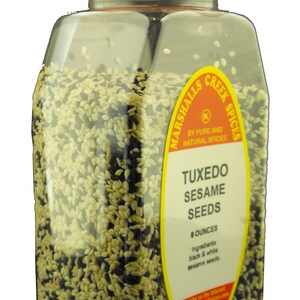 May include: A clear plastic jar filled with black and white sesame seeds. The jar has a red lid and a yellow label that reads "Marshalls Creek Spices" and "Tuxedo Sesame Seeds". The label also states "8 ounces" and "Ingredients: black & white sesame seeds".