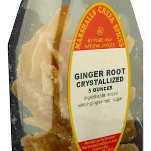 May include: A clear glass jar with a red lid filled with crystallized ginger root. The jar has a yellow label that reads "Marshalls Creek Spices" and "Ginger Root Crystallized 5 ounces". The label also lists the ingredients as "sliced whole ginger root, sugar".