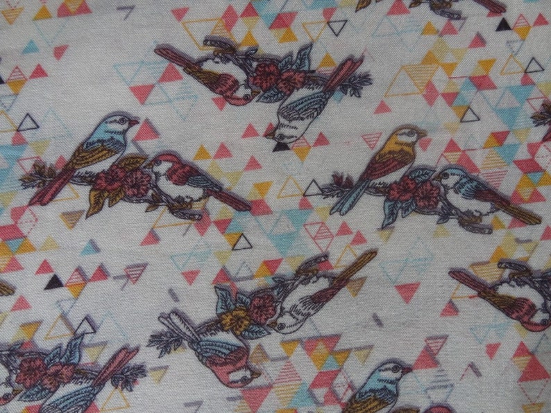 K&ouml;nnte beinhalten: Ein wei&szlig;er Stoff mit einem sich wiederholenden Muster aus bunten V&ouml;geln und geometrischen Formen. Die V&ouml;gel sind blau, gelb und braun mit rosa Bl&uuml;ten. Die geometrischen Formen sind Dreiecke in den Farben Rosa, Blau, Gelb und Grau.