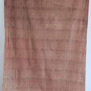 May include: A fabric with a vertical striped pattern in shades of brown and cream. The fabric is draped, with the bottom portion folded and gathered, revealing the pattern's continuity.