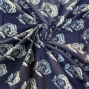 May include: Blue cotton fabric with a white floral pattern. The fabric is folded and shows the pattern repeating.