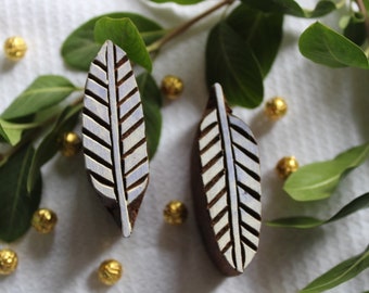 May include: Two wooden leaf-shaped stamps with white and brown details, arranged with green leaves and gold-coloured decorative spheres. The stamps have a detailed, symmetrical design, ideal for crafting or decorative purposes.