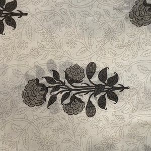 May include: White fabric with a black floral pattern. The pattern features stylized flowers and leaves.