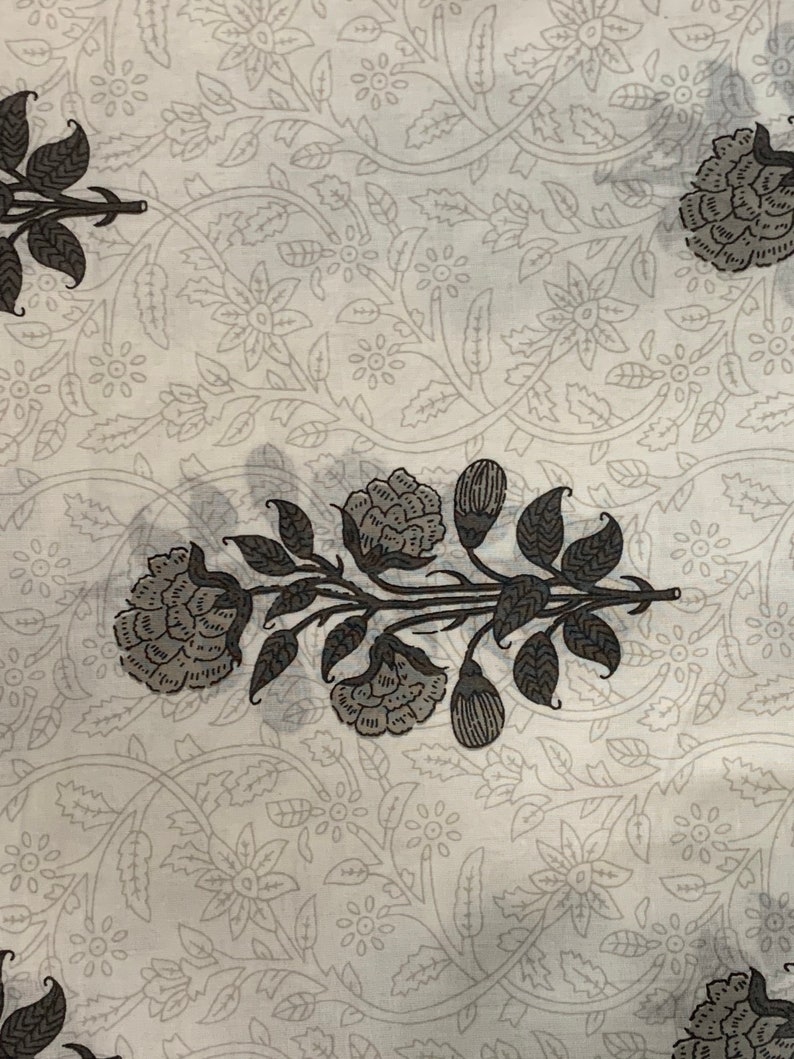 May include: White fabric with a black floral pattern. The pattern features stylized flowers and leaves.