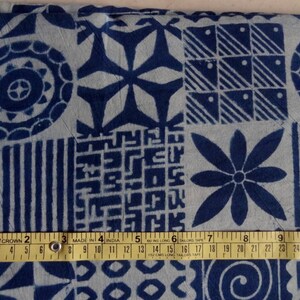May include: A close-up of a blue and white fabric with a variety of geometric patterns. The fabric is measured with a tape measure that reads "MADE IN INDIA".