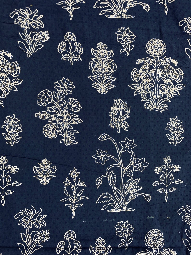 May include: A dark blue fabric with a white floral pattern. The pattern features various floral designs, including leaves, stems, and flowers.