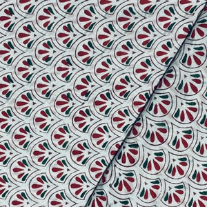 May include: White fabric with a repeating pattern of stylized, fan-shaped designs in dark red and green. The pattern is outlined in a dark brown color. The fabric is folded diagonally, showing the pattern's continuity.