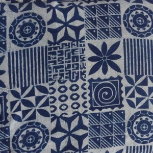 May include: A white fabric with a blue geometric pattern. The pattern includes circles, stars, squares, and flowers.