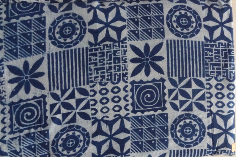 May include: A white fabric with a blue geometric pattern. The pattern includes circles, stars, squares, and flowers.