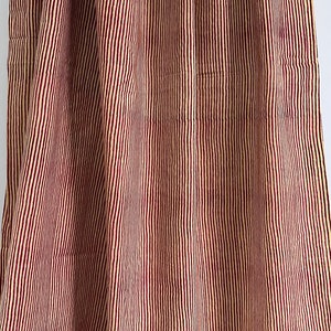 May include: Close-up of a fabric with vertical stripes. The stripes alternate between a light beige and a deep burgundy color. The fabric is draped, creating soft folds and shadows.