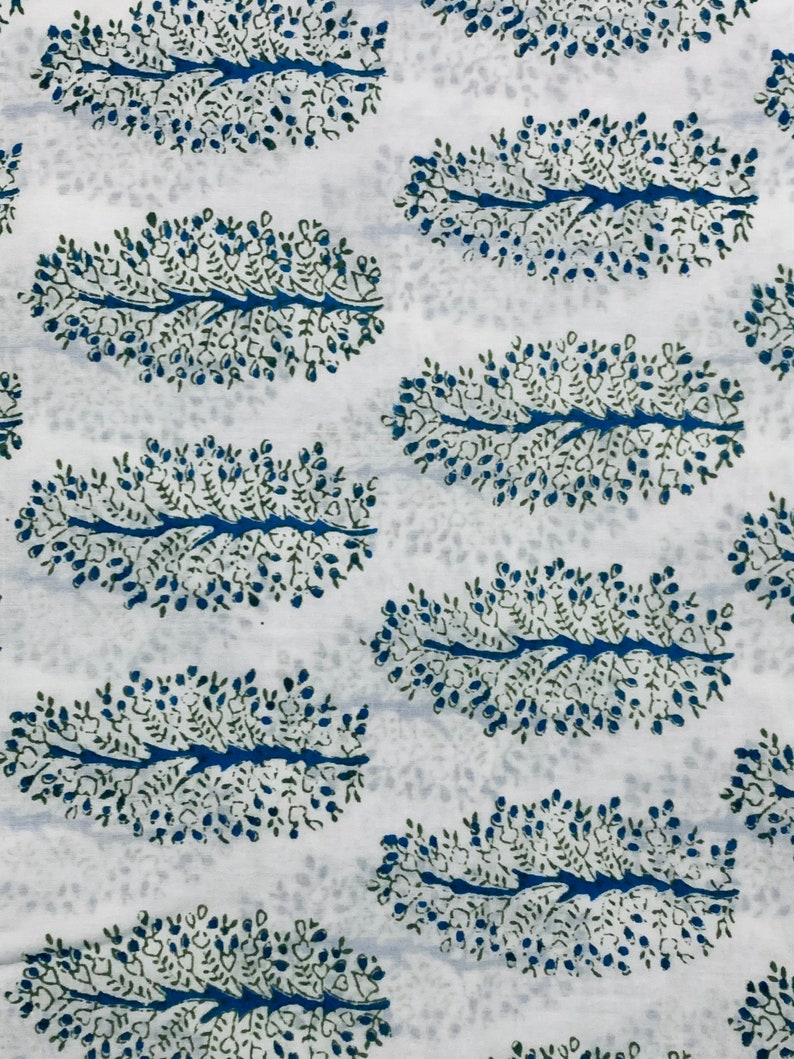 May include: White fabric with a blue and green floral pattern. The pattern is a repeating design of stylized leaves with small dots.