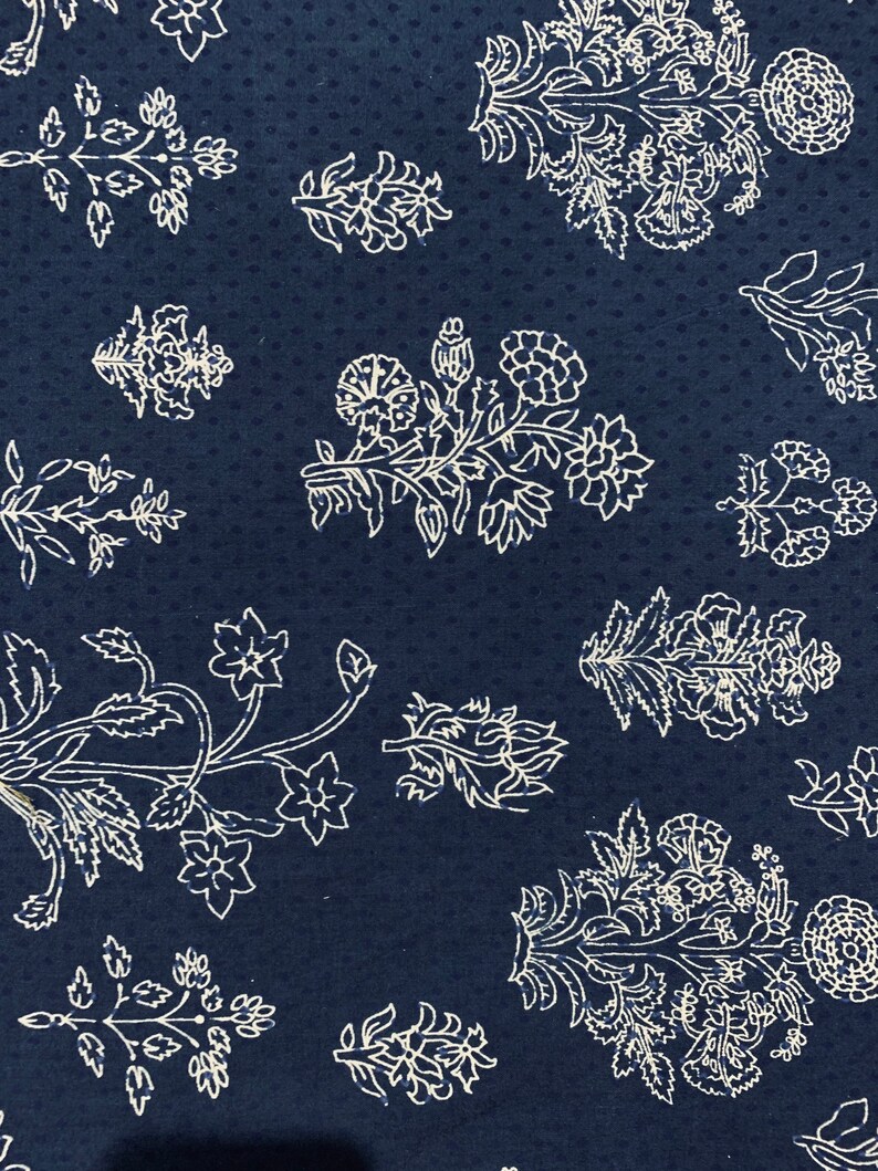 May include: A navy blue fabric with a white floral pattern. The pattern features a variety of flowers and leaves, all in a simple, elegant style.