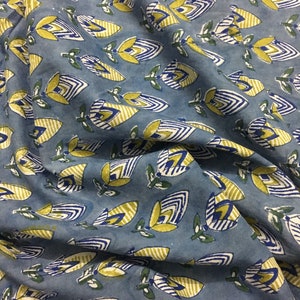 May include: Blue fabric with a repeating pattern of yellow and blue stylized flowers. The flowers have a striped design and are outlined in blue.