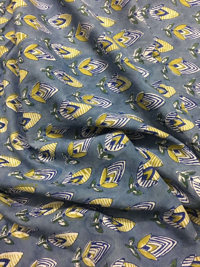 May include: Blue fabric with a repeating pattern of yellow and blue stylized flowers. The flowers have a striped design and are outlined in blue.