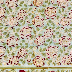 Peut inclure: Un tissu bleu clair avec un motif répétitif de fleurs blanches et jaunes avec des contours rouges. Les fleurs sont entourées de feuilles vertes. Le tissu a une bordure de fleurs rouges avec des feuilles vertes.