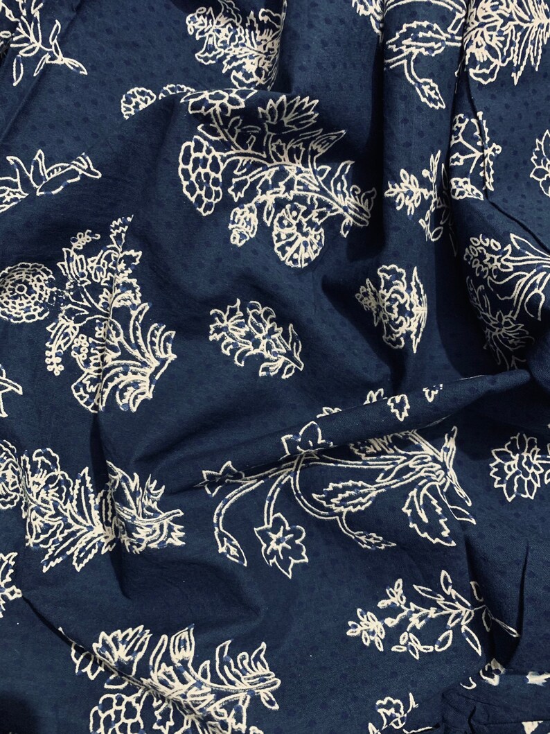 May include: A dark blue fabric with a white floral pattern. The fabric is textured and has a slightly wrinkled appearance.