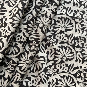 May include: Black and white fabric with a floral pattern. The fabric is folded and shows the pattern repeating.