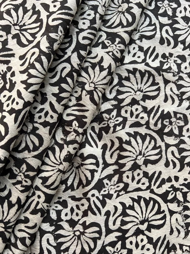 May include: Black and white fabric with a floral pattern. The fabric is folded and shows the pattern repeating.