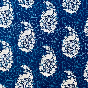 May include: A blue fabric with a white repeating pattern of birds perched on branches with flowers. The pattern is a traditional design.