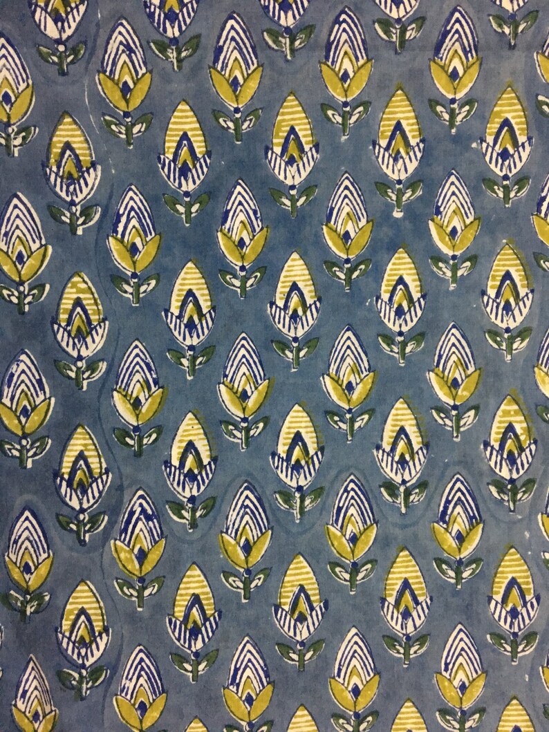May include: A blue fabric with a repeating pattern of yellow and blue stylized flowers. The flowers have a white outline and are arranged in rows.