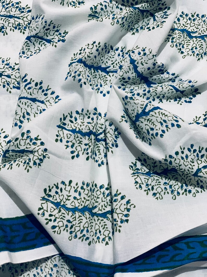 May include: White fabric with a repeating pattern of blue and green stylized trees. The fabric has a blue and green border.