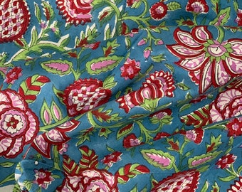 May include: Blue fabric with a floral print in shades of pink, red, and green. The flowers are stylized and have a traditional Indian design.