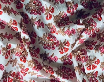 May include: White fabric with a repeating pattern of pink and red flowers with brown stems. The fabric is wrinkled and has a soft, natural texture.