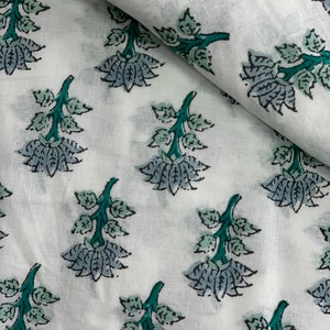 May include: White fabric with a repeating pattern of teal green and grey floral designs. The fabric has a soft, textured look.