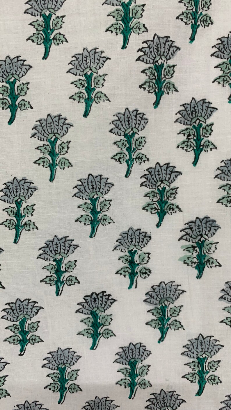May include: White fabric with a repeating pattern of grey and green floral designs. The flowers have five petals and are on a green stem with leaves.