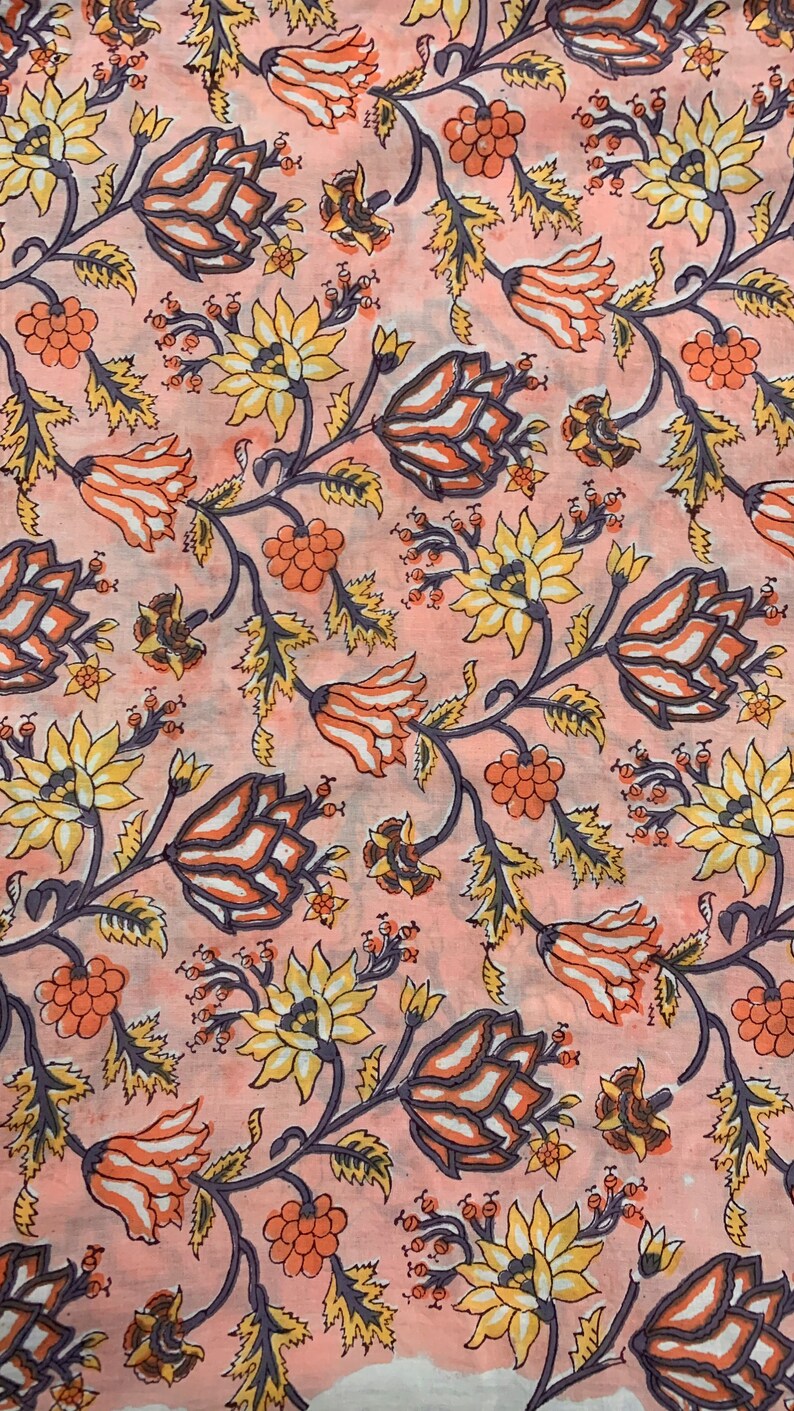 May include: A pink fabric with a floral pattern. The flowers are in shades of yellow, orange, and purple. The fabric has a vintage look.