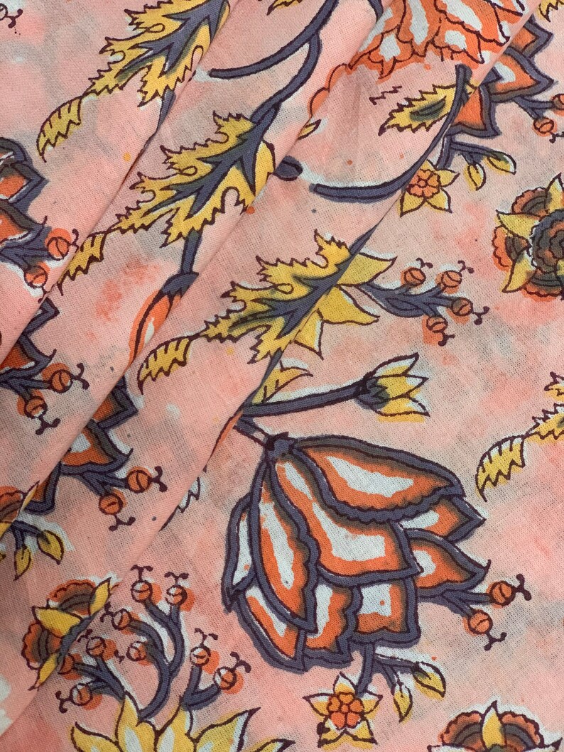 May include: Pink fabric with a floral print featuring yellow, orange, and gray flowers. The fabric has a subtle watercolor effect.
