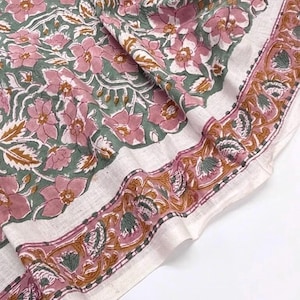 May include: A textile fabric featuring a block-printed floral pattern in shades of dusty pink, sage green, and muted gold on an off-white background. The design includes a central floral motif and a distinct decorative border with stylised leaves.