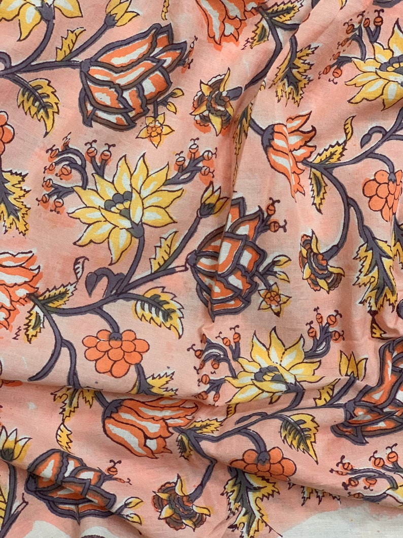 May include: Pink fabric with a floral print featuring orange, yellow, and gray flowers. The fabric has a wrinkled texture.