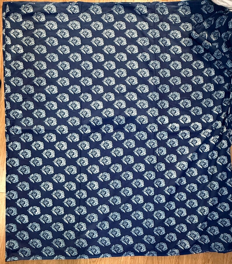 May include: A dark blue fabric with a white floral pattern. The fabric is a repeating pattern of stylized flowers.