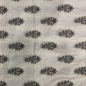 May include: White fabric with a repeating pattern of black floral sprigs. The fabric has a subtle texture.