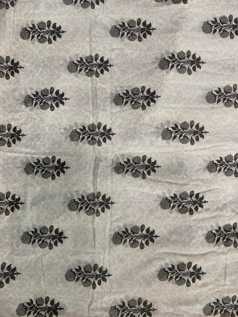 May include: White fabric with a repeating pattern of black floral sprigs. The fabric has a subtle texture.