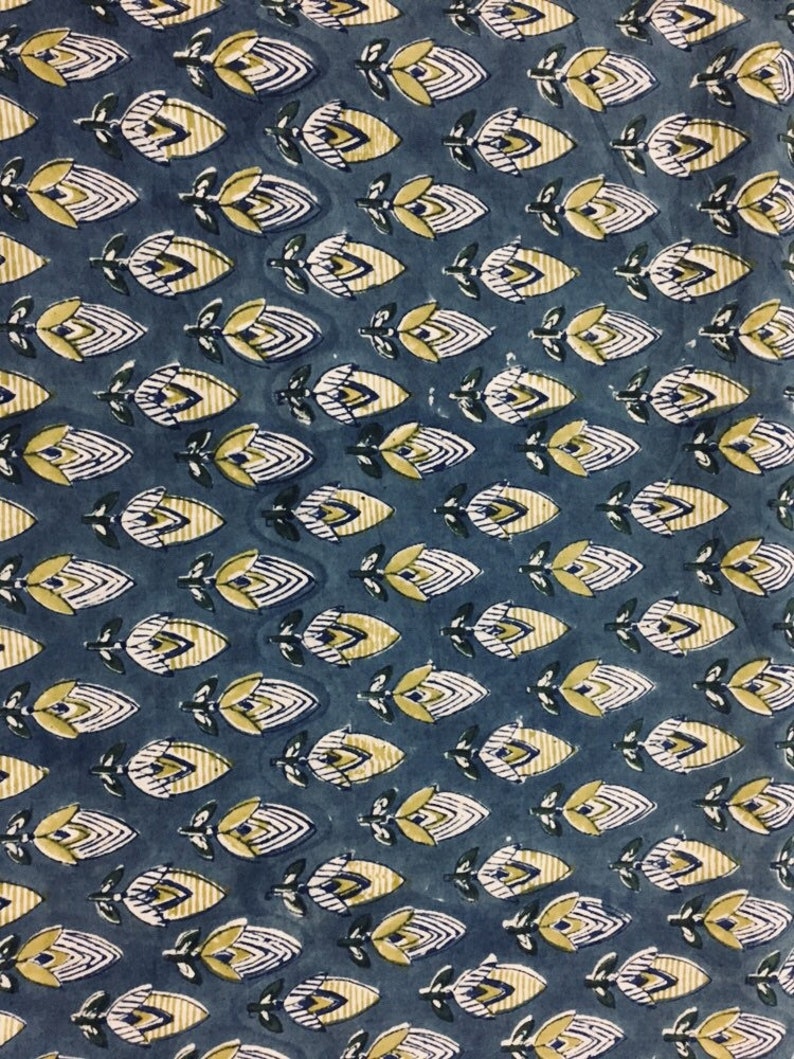 May include: A blue fabric with a repeating pattern of yellow and white stylized flowers. The flowers have a geometric design and are arranged in rows.